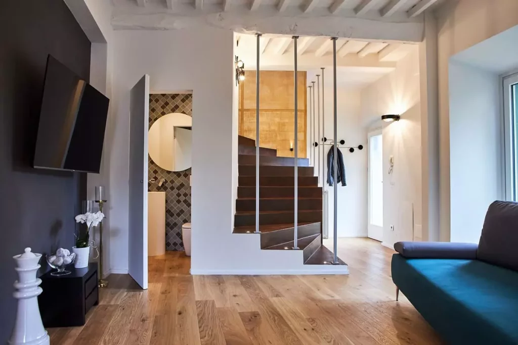 Interno di una casa unifamiliare moderna con scala in resina effetto ruggine e parquet in rovere chiaro, progettata da [Nome studio di architettura]. Il design è moderno e minimalista, con la scala che funge da elemento focale dell'ambiente.