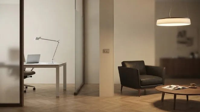 Interno di ufficio professionale con illuminazione a due registri: luce neutra e funzionale per la postazione operativa e luce calda e dimmerabile per la zona colloquio