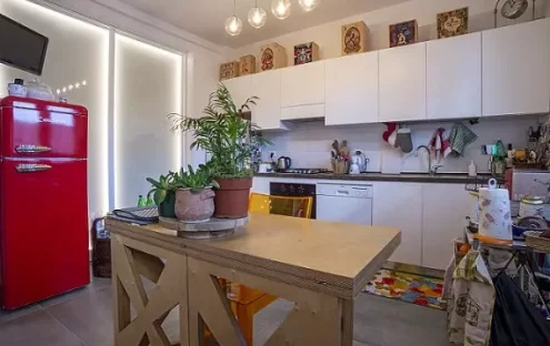 Foto di una cucina ristrutturata con una parete in vetro retroilluminato che la divide dal soggiorno. Il progetto di ristrutturazione ha creato un ambiente elegante e sofisticato. La parete in vetro permette di mantenere lo spazio aperto e arioso